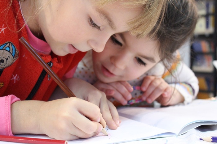 Niños pequeños escribiendo sobre un cuaderno